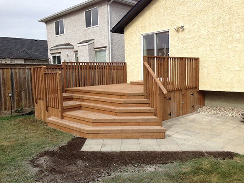 Treated brown deck with decorative angled staircase. Dynasty Wave patio in Sierra Grey.