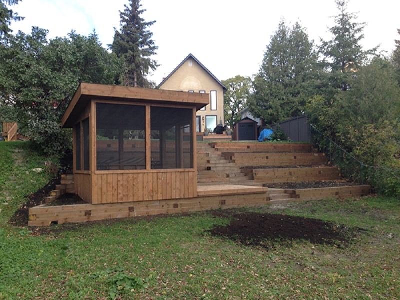 Treated brown retaining wall with built-in gazebo on bank of Assiniboine river