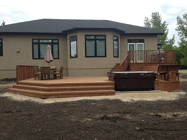 Complete yard installation. Two tier treated brown deck with built-in hot tub and storage access door, patio with fire pit and seating wall, black granite boulders, mulch, lighting, arbors