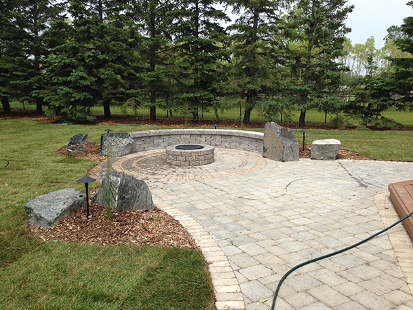 Complete yard installation. Two tier treated brown deck with built-in hot tub and storage access door, patio with fire pit and seating wall, black granite boulders, mulch, lighting, arbors