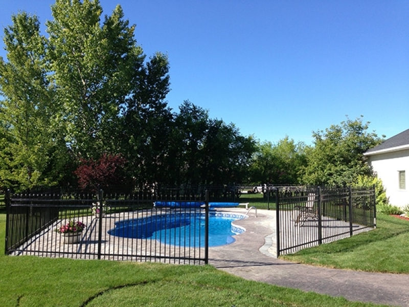 Roman pavers around pool with black ornamental fence. Sod installation.