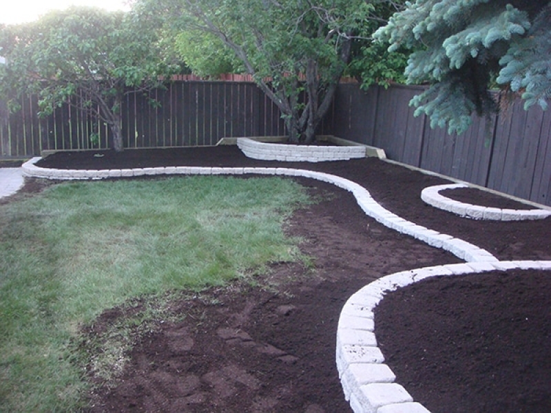 Holland paving stone patio. Roman Stack Stone retaining wall planters filled with soil.