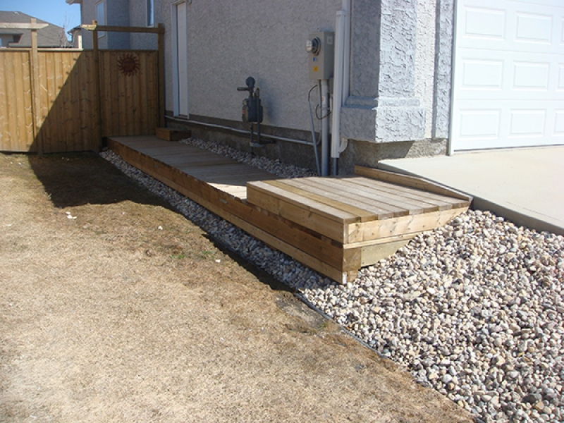 Wooden boardwalk at side of house.