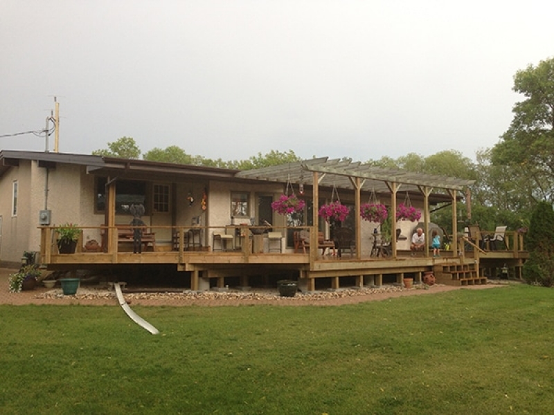 Large treated green deck at the back of a house in a rural setting