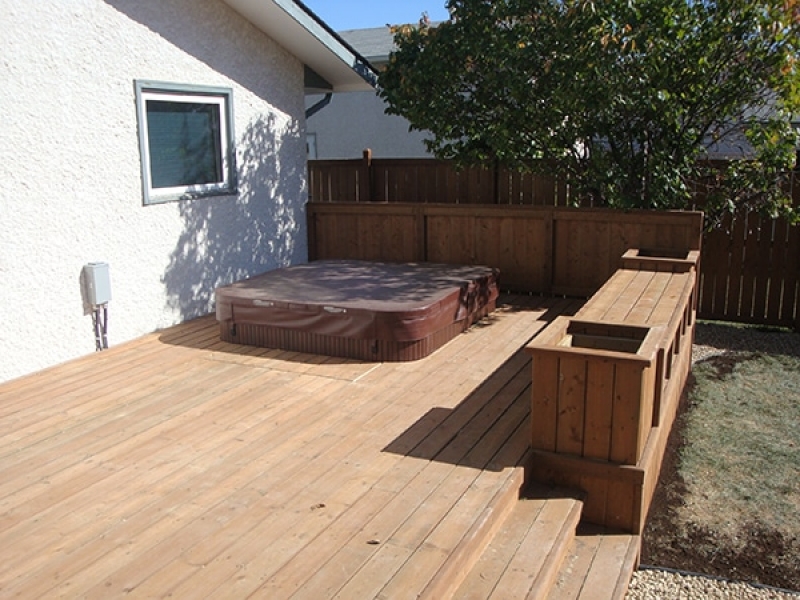 Treated brown deck with built-in hot tub, benches, and planters.