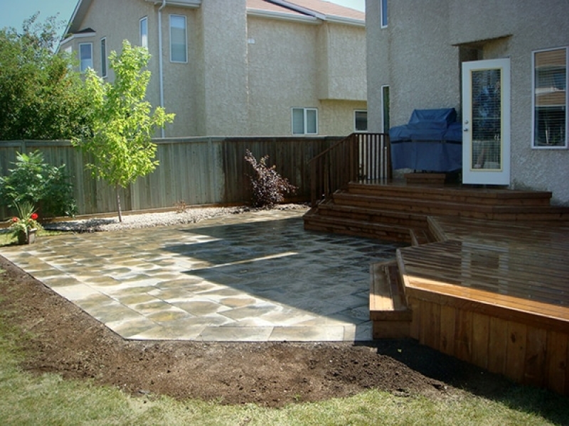 Treated brown deck with full length staircase leading to partially wet Dynasty slate patio.