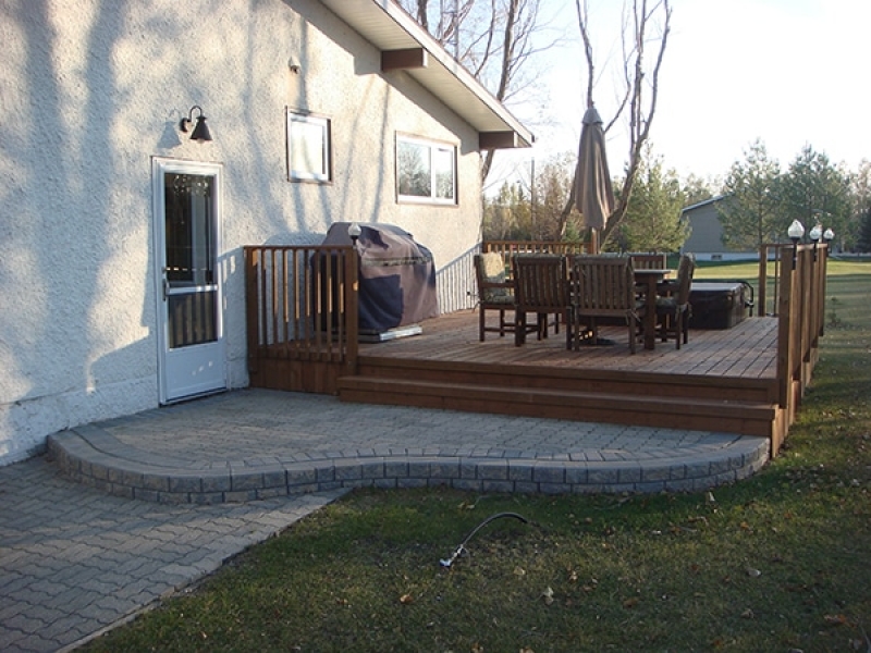 Treated brown deck with retaining wall landing and built-in hot tub.