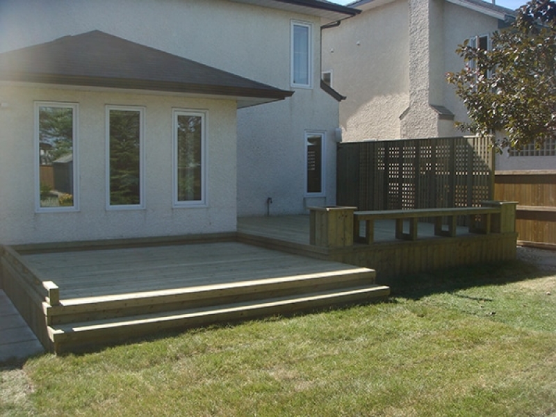 Treated green deck with built-in benches, planters, and custom lattice privacy wall. Built-in storage cupboard.