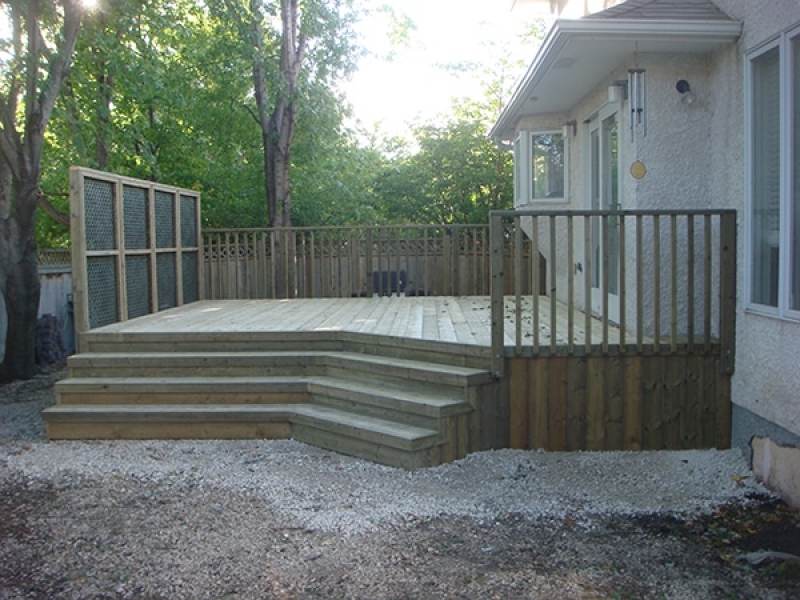 Treated green deck with wide angled stairs and lattice privacy wall.