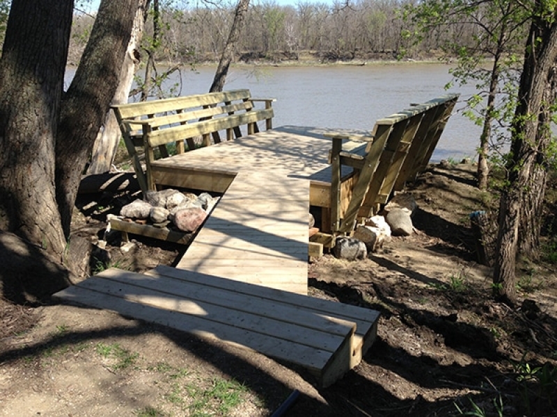 Treated green riverside deck with benches.