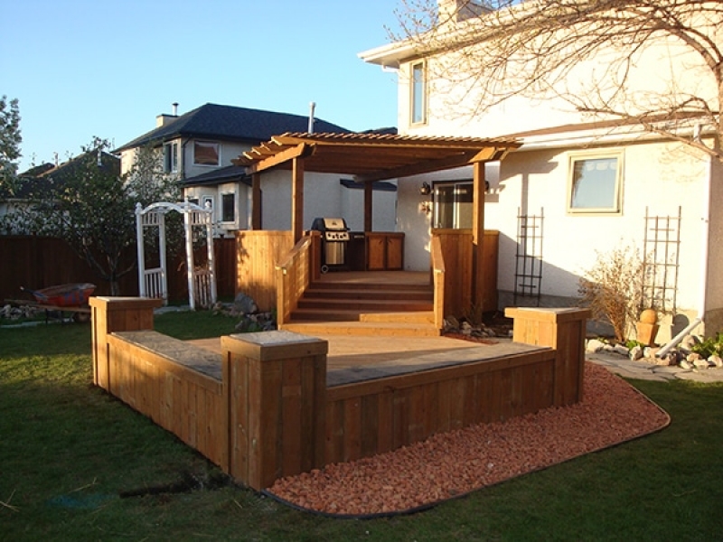 Treated brown deck with built-in cabinets, counters, benches, and pergola.