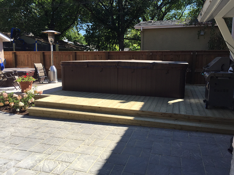 Navarro patio in Sierra Grey adjacent to treated green deck around swim spa