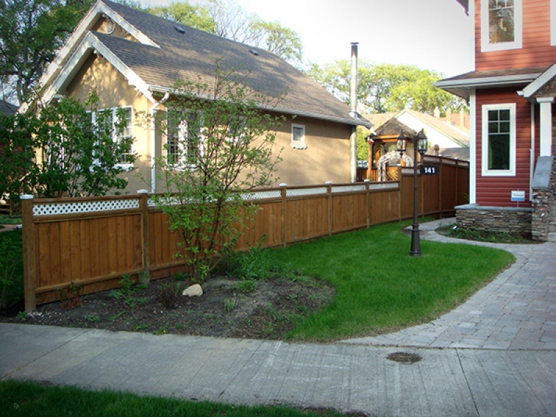 Complete yard renovation. Roman paving stones and retaining walls. Plantings and boulders surrounded by red wood mulch. Treated brown fence with white lattice top (Rock Gardens)