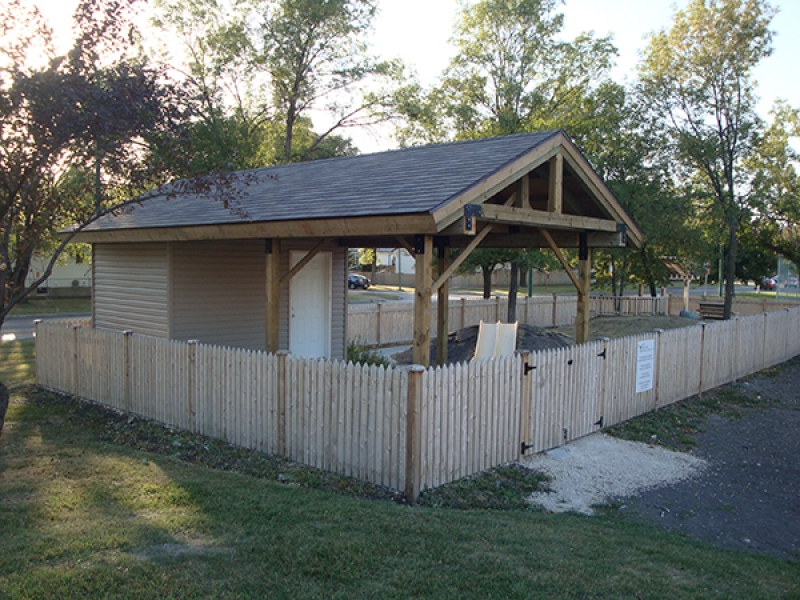 Daycare playground enclosed by cedar fence. Shelter with built-in shed, stream bed, sand box, arbor, benches, etc