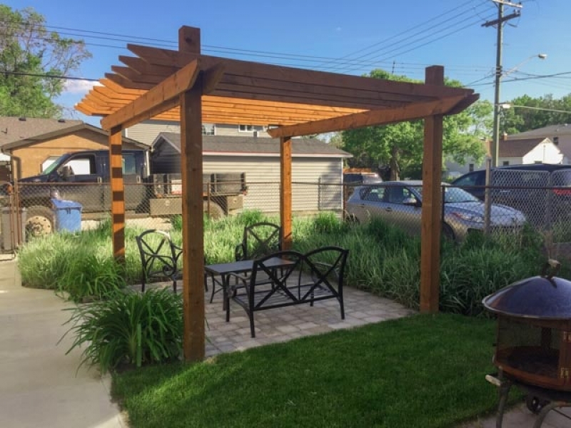 Small rear deck, arbor over paving stone patio, sod, soil, and plants