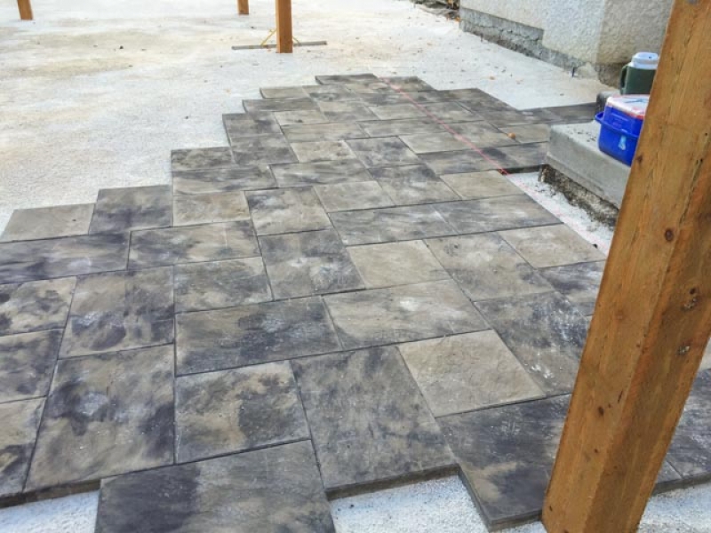 Large patio with Dynasty Slate blocks in sierra grey, posts for arbor and fence