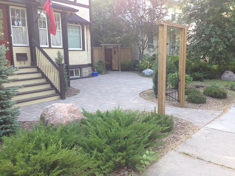 Roman paving stones covering large portion of yard. Plants and wood mulch in front