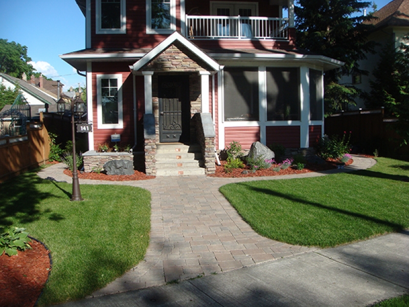 Complete yard renovation. Roman paving stones and retaining walls. Plantings and boulders surrounded by red wood mulch. Treated brown fence with white lattice top (Patios)