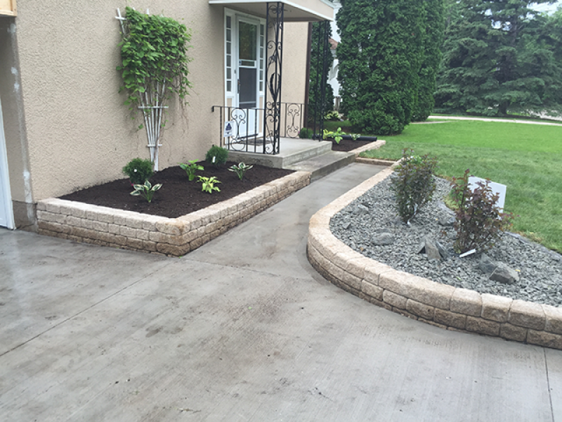 Front beds defined by Roman Stack retaining wall in Desert Buff