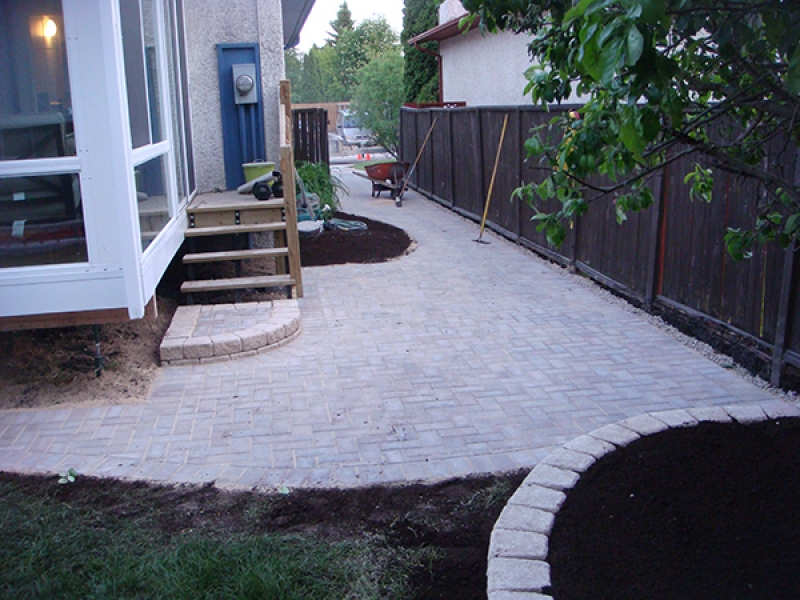 Holland paving stone patio. Roman Stack Stone retaining wall planters filled with soil.