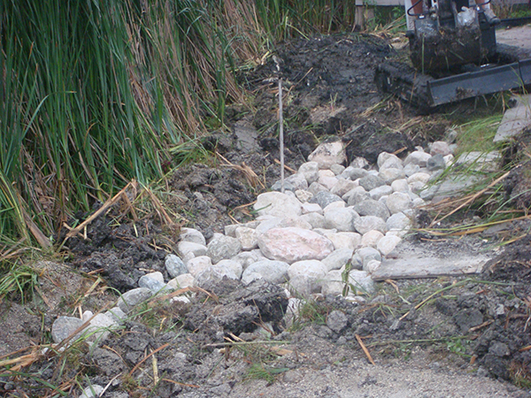 Boulders being installed to reduce erosion by man-made lake (rock gardens, grading and drainage).jpg