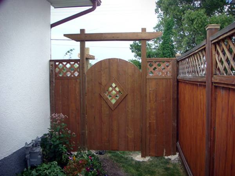 Decorative treated brown gate and adjacent sections added to existing fence (fences)