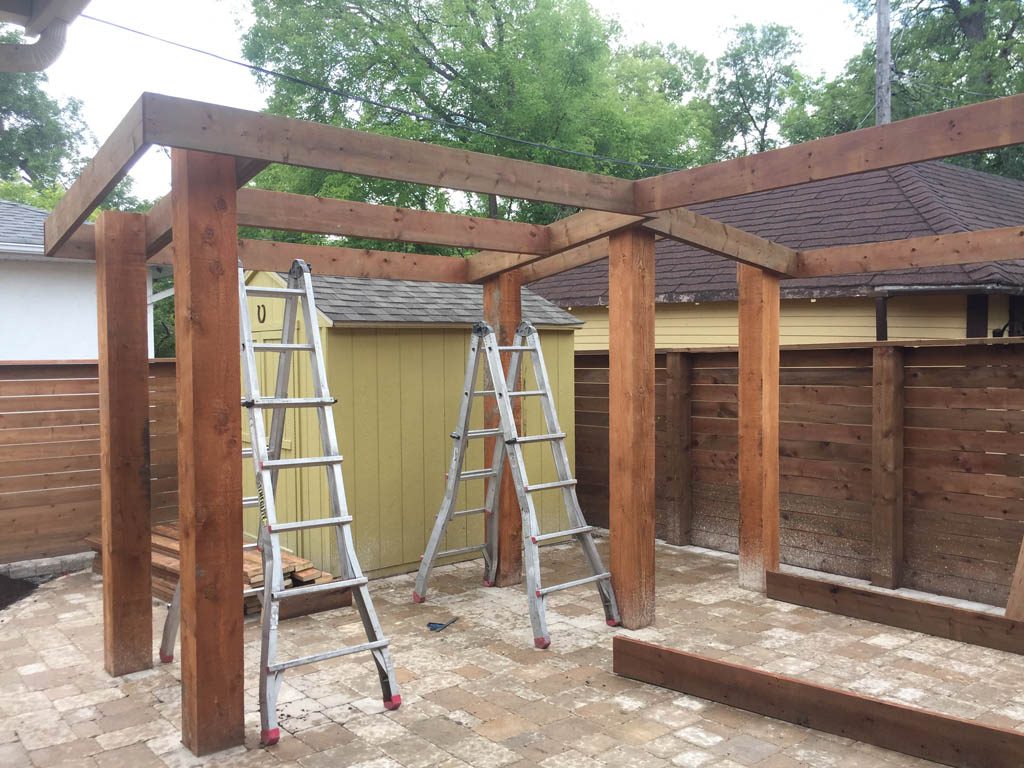Treated brown pergola with hanging bench, fixed bench, Roman paving stones, planter with trellis, etc