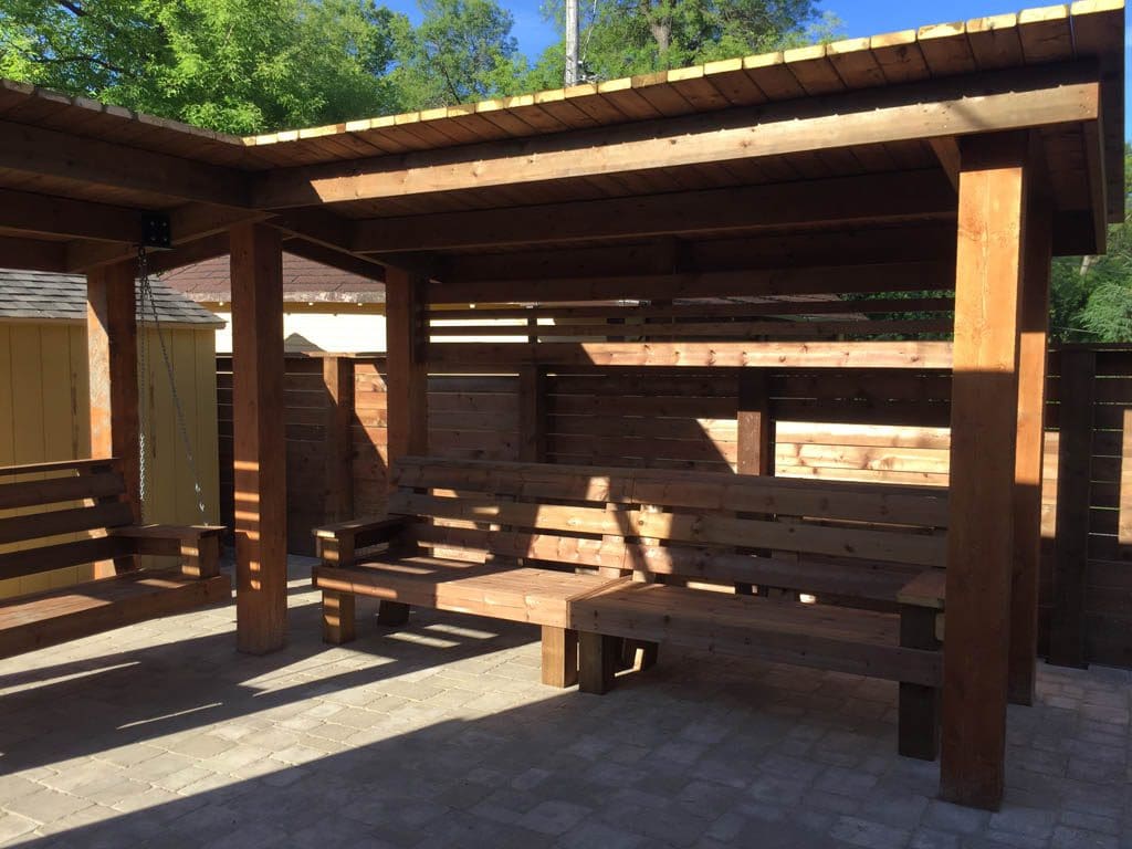 Treated brown pergola with hanging bench, fixed bench, Roman paving stones, planter with trellis, etc