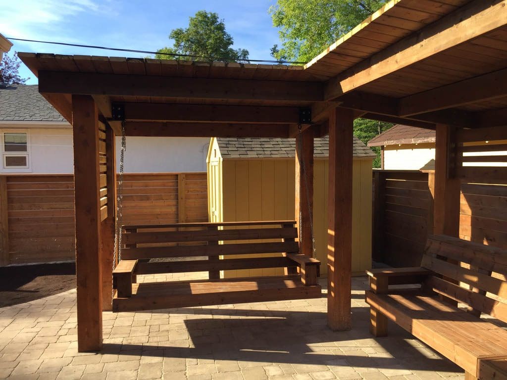 Treated brown pergola with hanging bench, fixed bench, Roman paving stones, planter with trellis, etc