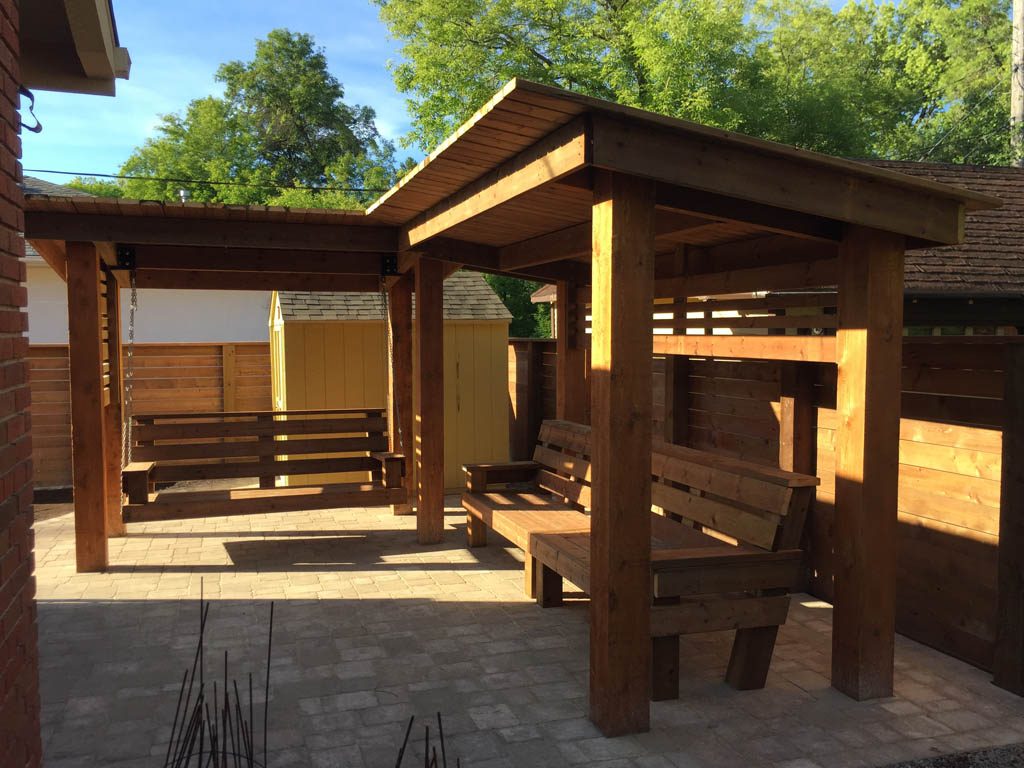 Treated brown pergola with hanging bench, fixed bench, Roman paving stones, planter with trellis, etc