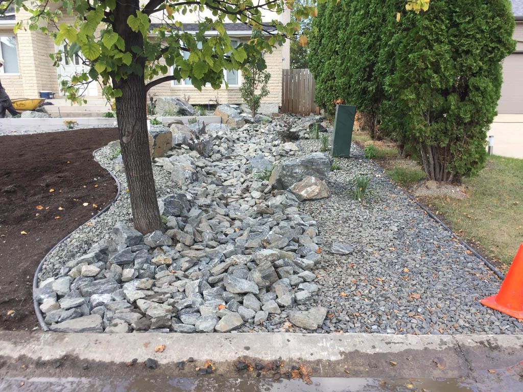 Front yard renovation with Architextures retaining wall, black granite, plants, sod