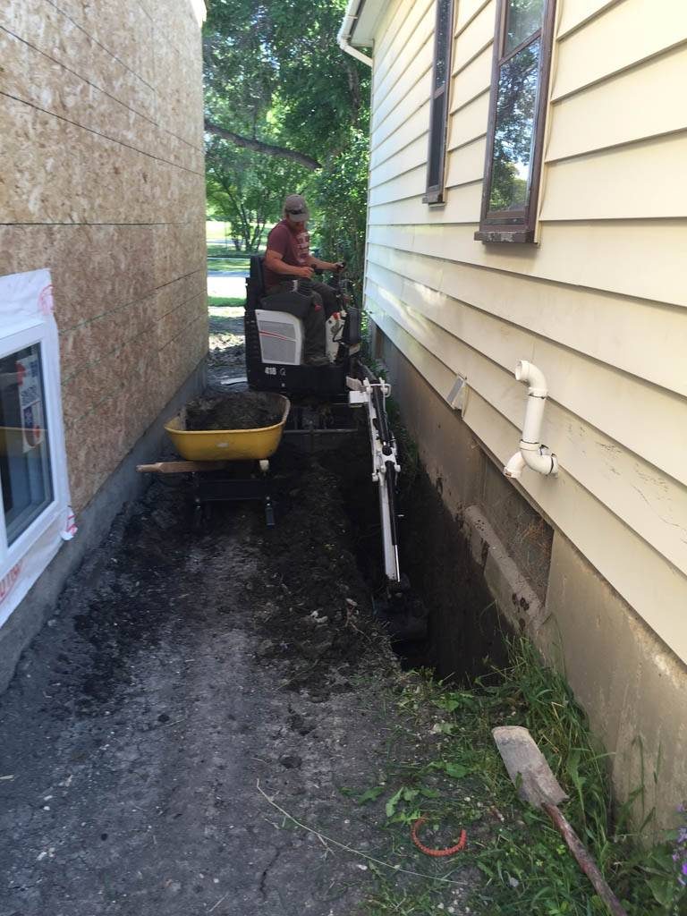 Mini excavator digging for foundation repair (Bobcat + excavator service)