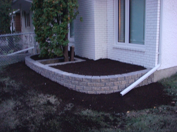 Stack Stone retaining wall planter at front of house